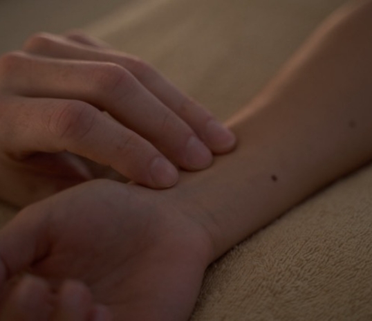 A person checks their pulse before acupuncture for anxiety while lying on a fabric surface.