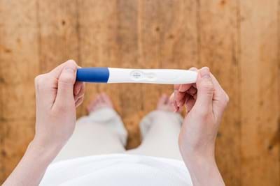 Person holding a positive pregnancy test, symbolizing hope in TCM and Chinese herbal medicine.