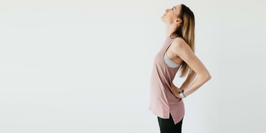 Woman standing with hands on hips, looking upward, embodies confidence in acupuncture.