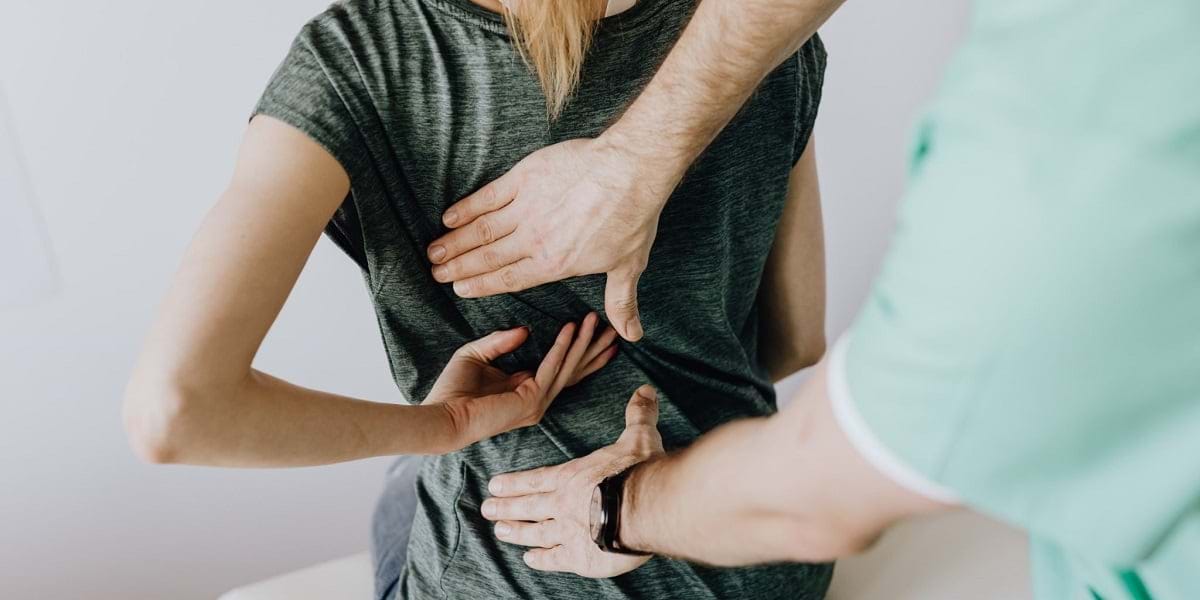 Person receiving a back examination from a healthcare professional trained in TCM.