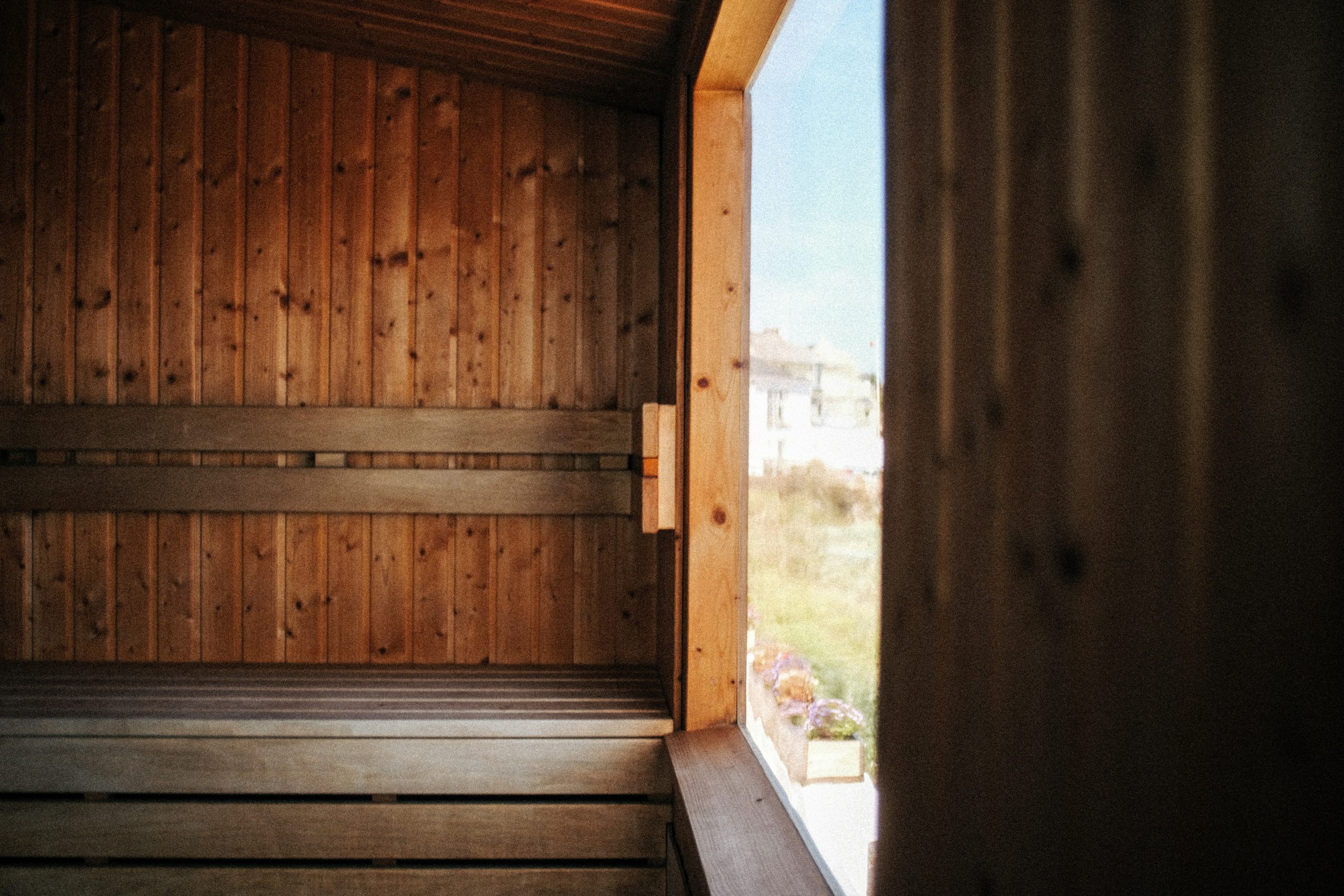 Wooden sauna interior with benches, large window, and touches inspired by TCM traditions.