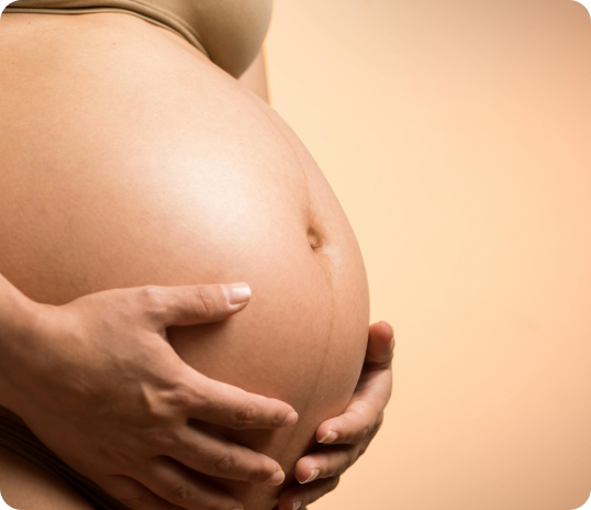 Close-up of a pregnant belly with hands gently resting, symbolizing TCM and nurturing care.