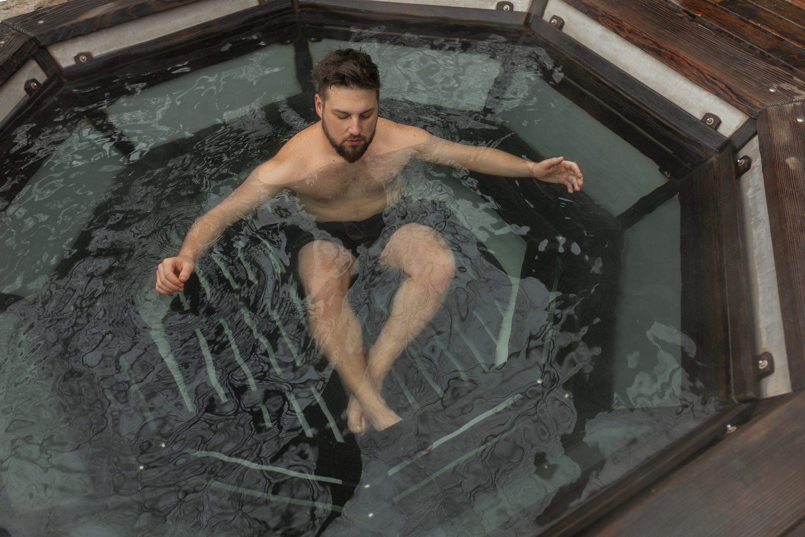 A man enjoys a small octagonal wooden hot tub after a tcm and chinese herbal medicine session.