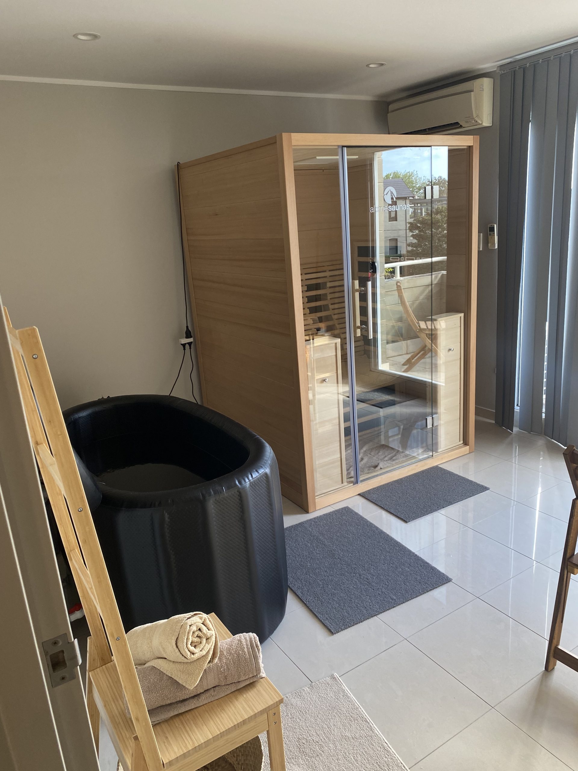 A modern room with a wooden sauna, black tub, towels, and touches of TCM tranquility.