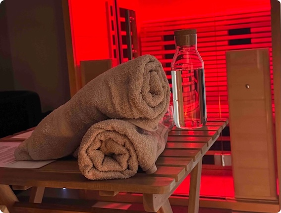Two rolled towels and a glass water bottle rest on a bench, evoking a TCM-inspired ambiance.