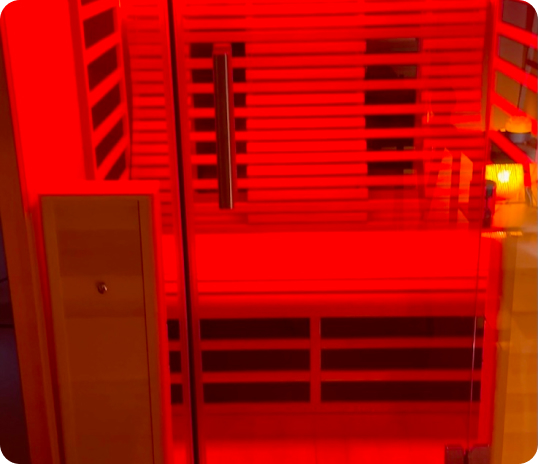 Glass door to a red-lit infrared sauna, evoking a tcm-inspired wooden interior.