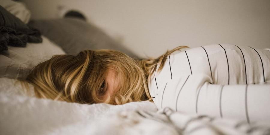 Person lying face down on a bed in a striped shirt, suggesting post-acupuncture relaxation.