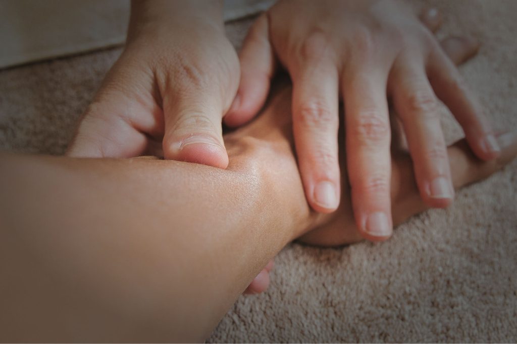 Close-up of hands massaging a foot, inspired by TCM and Chinese herbal medicine practices.