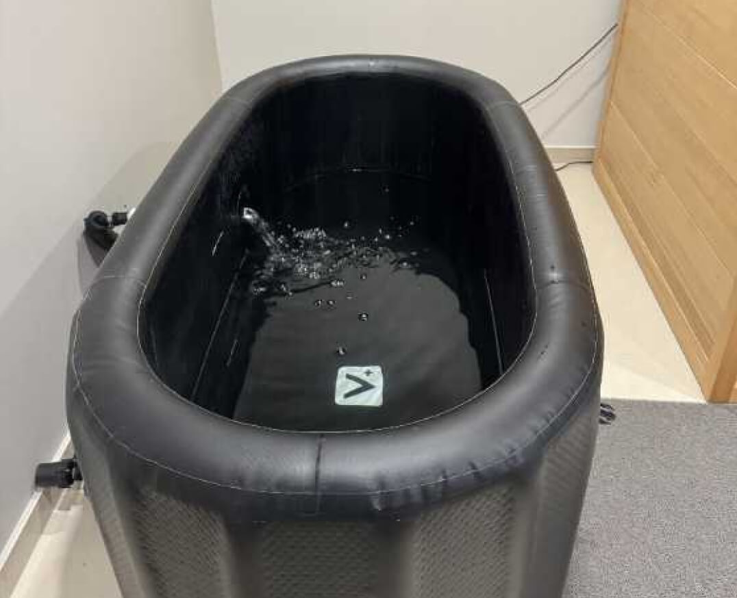 A black inflatable tub is being filled with water in a cozy TCM wellness room.