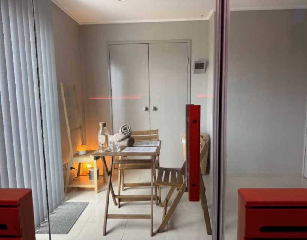 Small room with wooden table, chairs, towels, water, soft lamp lighting, and TCM touches.