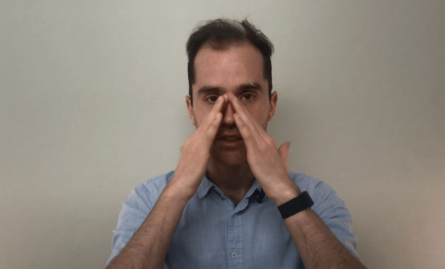 Person touching both sides of their nose, demonstrating an acupuncture or TCM technique.