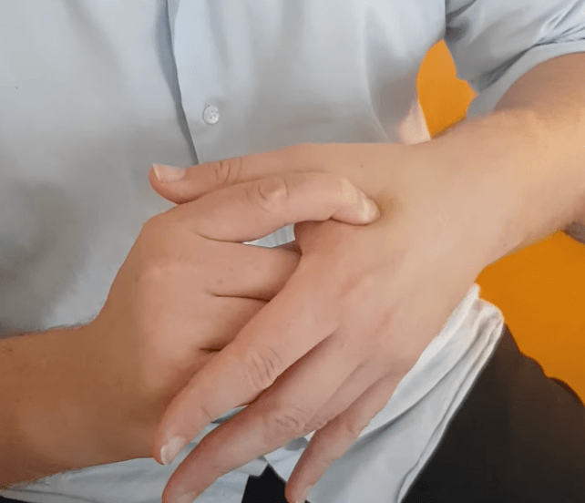 A person in a light shirt practices TCM by cracking the knuckles of their left hand.