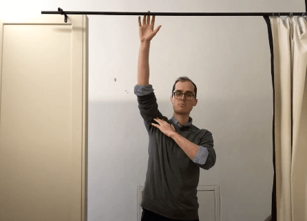 Person standing indoors, posing as if demonstrating an acupuncture or TCM technique.
