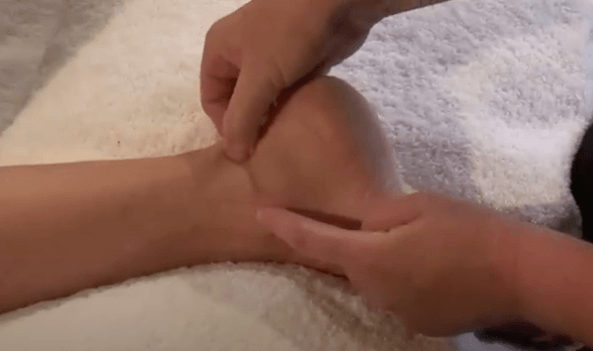 Hands massaging the ankle, a soothing practice often used in TCM and acupuncture therapy.