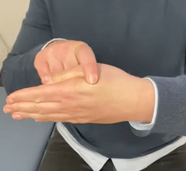 Person pressing on the base of their thumb, a common acupressure point in TCM.