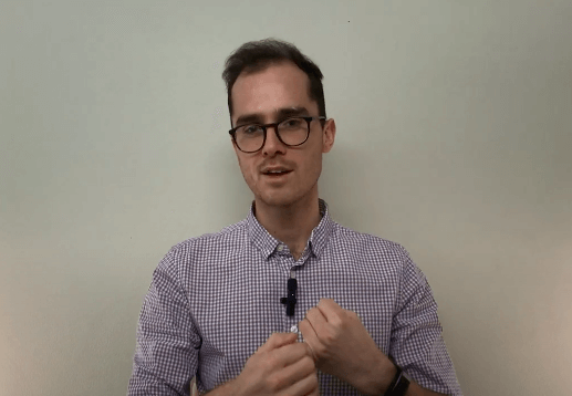 Man in glasses and checkered shirt discusses TCM, hands clasped in front of a plain wall.