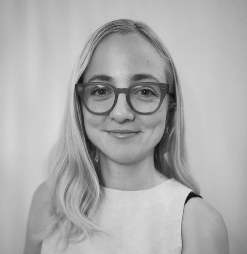 Woman with long blonde hair and glasses, smiling, promotes acupuncture against a plain background.